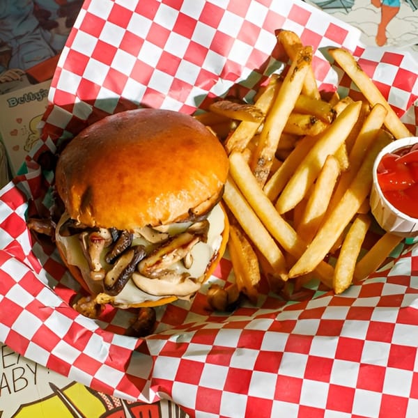Mushroom burger with melted cheese and a side of golden french fries with ketchup.